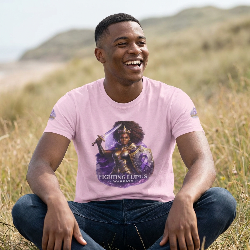 Person wearing a pink t-shirt with a graphic design sitting in a field.